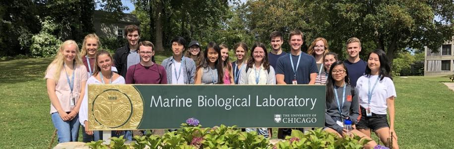 Group of students standing behind a sign that says "Marine Biological Laboratory"