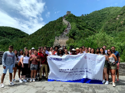 A group of students on the Great Wall of China holding a banner for the Wanxiang Ambassador Fellows Program